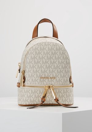 Piccolo zaino beige Michael Kors con motivo logo MK, manico in pelle marrone, cerniere dorate e due tiretti frontali su superficie bianca.