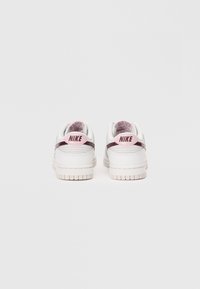 Ténis Nike com um upper de couro branco, acentos rosa no calcanhar e uma entressola texturizada. Apresenta um colarinho acolchoado e detalhes costurados.