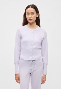 Πλεκτή ζακέτα λεβάντας με στρογγυλή λαιμόκοψη, μακριά μανίκια και κουμπιά στο μπροστινό μέρος. Πλεκτή ζώνη στη μέση και ρεβέρ στα μανίκια, απαλό ύφασμα. Άνετη εφαρμογή.