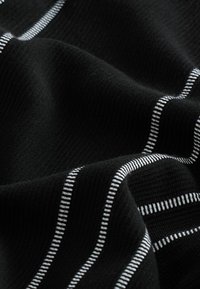 Tela negra con rayas blancas horizontales. La textura parece suave y lisa, con un patrón de punto visible en el material.