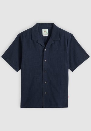 Tumesinise lühikeste varrukatega nööpidega särk, millel on tekstuuriga kangas ja laagrikrae, laotatud laiali heledal taustal.