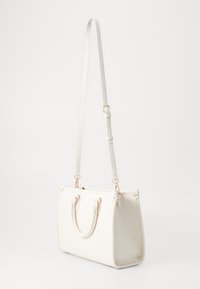 Borsa a mano in pelle bianca con due manici superiori, tracolla regolabile e accessori metallici color oro. Texture liscia, forma rettangolare, accessori minimi.