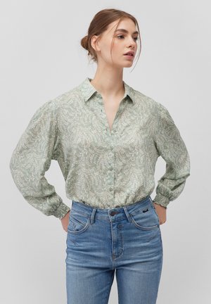 Light green button-up shirt with a floral pattern, long puff sleeves, and elastic cuffs, paired with blue denim jeans.