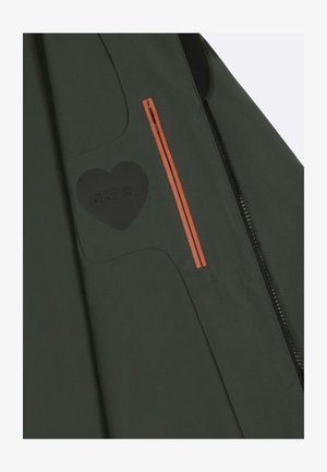 Sezione di giacca verde scuro con una toppa a forma di cuore nera e una tasca con cerniera a strisce verticali arancioni accanto a una cucitura con cerniera nera.