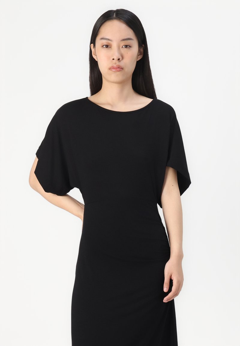 Zwarte jurk met een relaxte pasvorm, korte mouwen en een ronde halslijn. Gemaakt van een soepele stof met een aansluitende silhouet.