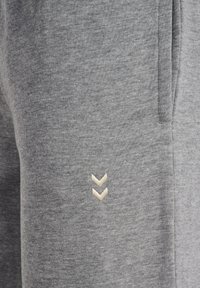 Szare bawełniane spodnie dresowe o miękkiej fakturze, z haftowanym jasnobeżowym logo po boku oraz bocznymi kieszeniami na przechowywanie.