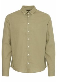 Cămașă lungă cu mânecă lungă de culoare verde deschis, cu guler ascuțit. Prezintă butoane albe și un logo subtil pe piept. Material texturat.