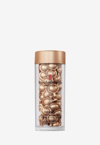 Genomskinlig cylindrisk behållare med lock i guld, fylld med guldglänsande, geléliknande kapslar märkta "VITAMIN C Ceramide Capsules."