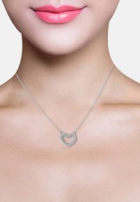 Silverhänge med hjärtform, prytt med små gnistrande stenar, hängande från en delikat kedja.