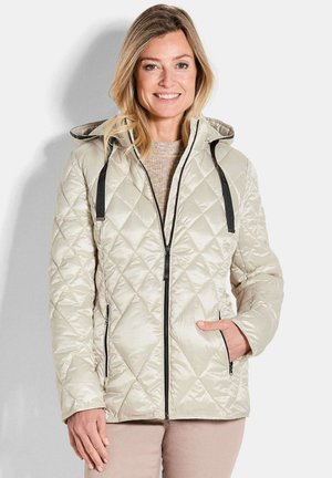 Beige gewatteerde jas met een capuchon, voorzien van zwarte accenten, een voorrits en twee zijzakken. Glad, glanzend textuur met een ruitpatroon.