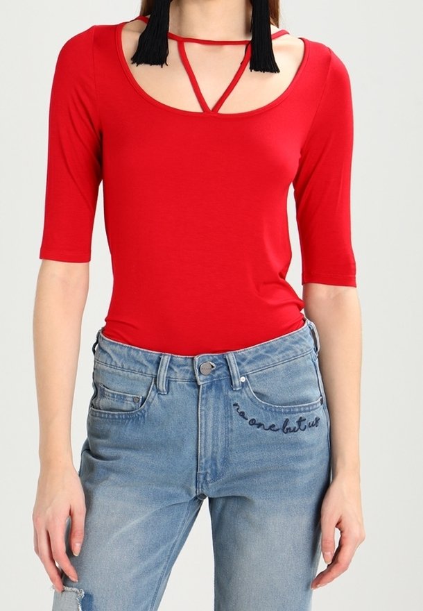 Body ajustado rojo con mangas cortas y un diseño de escote con tiras, combinado con pantalones vaqueros de denim desgastados de color azul claro que tienen texto bordado.