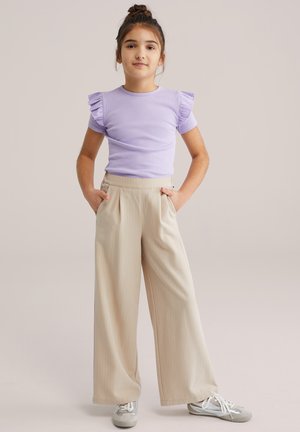 Lila kratka majica s kratkimi rokavi in volančki na ramenih, v kombinaciji z bež širokimi hlačami z belimi črtami in sivimi supergami, s stranskimi žepi.