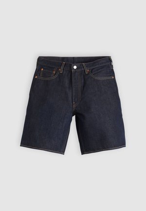 Σκούρα τζιν σορτς με πέντε τσέπες, πορτοκαλί ραφές και κλασική εφαρμογή. Το ύφασμα έχει λεία υφή με ελαφριά γυαλάδα.