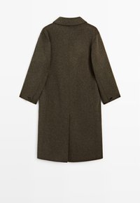 Cappotto di lana verde oliva con taglio dritto, maniche lunghe e un colletto piccolo. Presenta un singolo bottone su ciascun polsino e uno spacco sul retro.