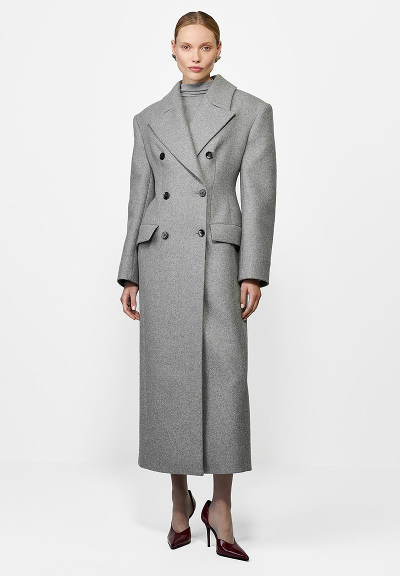 Szary dwunapiersiowy płaszcz z dużymi klapami, z dwoma przednimi kieszeniami, o długiej sylwetce i teksturowanej tkaninie.