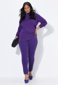 Lila stickad tröja med diamantmönster och utsmyckningar, ihop med enfärgade lila leggings och avslutad med lila klackar och en svart clutch.