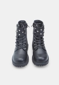 Stivaletti neri in pelle con punta rotonda, caratterizzati da un design con lacci, chiusura con zip e borchie a forma di cuore in argento sul risvolto.