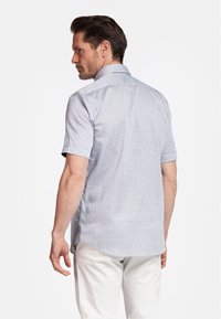 Korte mouw shirt in lichtblauw met een geometrisch patroon; voorzien van een klassieke kraag en een ontspannen pasvorm, gemaakt van lichte stof.