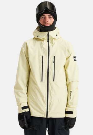 Geel waterdichte jas met een hoge kraag, zwarte ritszakken en GORE-TEX merk. Draag deze met zwarte handschoenen en een skimuts.