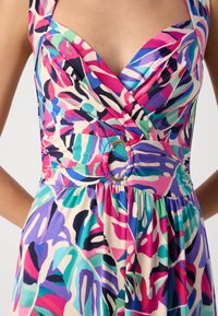 Abito floreale multicolore con scollatura profonda, vita arricciata e un accento circolare. Realizzato in tessuto morbido con motivi vivaci in rosa, verde e blu.
