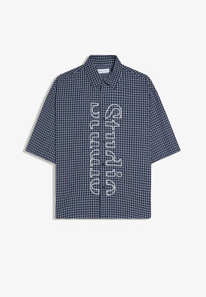 Navy blue short-sleeve button-up shirt with white checkered pattern and vertical white outlined text reading "Studium" down the front.