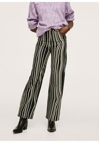 Pantalons à larges jambes rayés verticalement en noir et crème avec une taille haute, associés à un pull en maille texturé de couleur violet clair et des bottines noires.