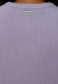 Maglione di cotone lilla chiaro con texture a coste, scollatura rotonda e un piccolo tag argentato sul retro.