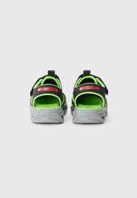 Svarta och neongröna sandaler med rundad form, med en grå sula och justerbar rem, som visar en ventilerande design och texturerad innersula.