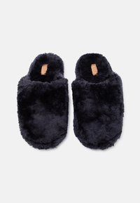 Ζευγάρι μαύρες, μαλακές παντόφλες χωρίς πίσω μέρος με αφράτη υφή, σε λευκό φόντο.