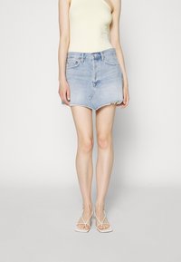 Helles blaues Jeans-Minikleid mit rohem Saum, taillierter Passform, Fünf-Taschen-Stil und Metallknopfverschluss, kombiniert mit einem gelben gerippten Tanktop.