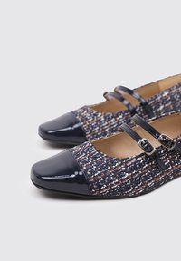 Chaussures Mary Jane en tissu bleu foncé avec des éclats multicolores ; bout en cuir verni bleu marine brillant et brides à double boucle.