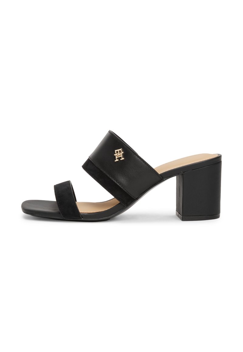Schwarze Absatzsandalen mit zwei breiten Riemen, einer aus glattem Leder und einer aus strukturiertem Wildleder. Sie verfügen über einen quadratischen Blockabsatz und ein goldfarbenes Logo-Detail.