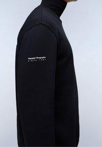 Czarny sweatshirt z wysokim kołnierzem, wykonany z miękkiego materiału. Na rękawie znajduje się biały nadruk "Napapijri Geographic" oraz "SINCE 1987".