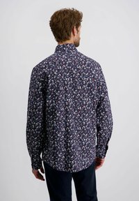 Langarmshirt in marineblauw met een bloemenpatroon in het wit, rood en blauw. Voorzien van een standaard kraag en knoopmanchetten, gemaakt van zachte stof.