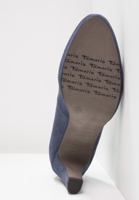 Scarpa con tacco alto in suede blu navy, con punta appuntita e tacco a blocco piccolo. La suola presenta il nome del brand 'Tamaris' e la misura 41 stampati.
