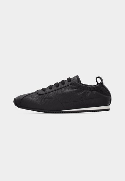 Μαύρο sneaker χαμηλού προφίλ με υφή, σχέδιο με κορδόνια, ελαστική γλώσσα αστραγάλου, ταινία τράβηγματος στη φτέρνα και λεπτή λευκή ρίγα στη σόλα.