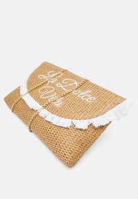Vävd halmclutch med vit fransdetalj, broderad text "La Dolce Vita" och en guldkedja för stängning.