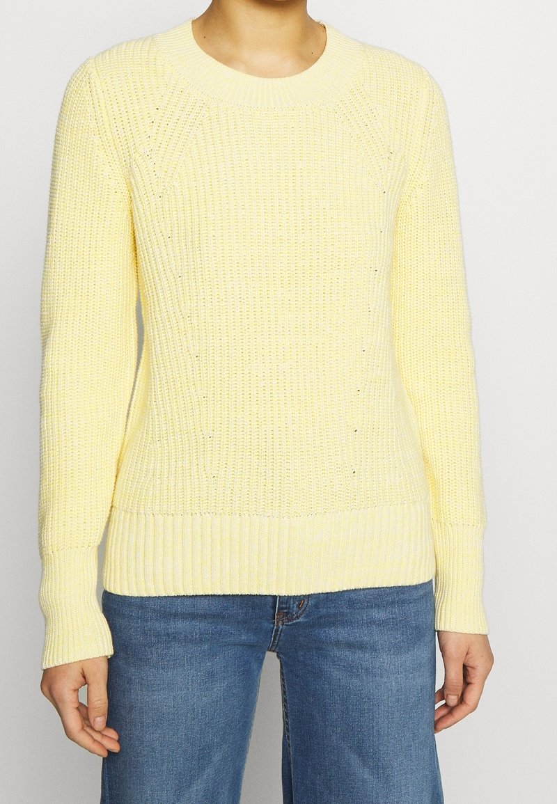 Gulstickad tröja med ett strukturerat mönster, rund halsringning och ribbade ärmslut och nederkant. Matchad med blå vida jeans.