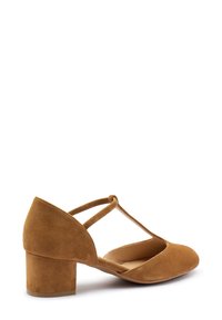 Scarpe in suede marrone a tacco basso con punta arrotondata e design con cinturino incrociato, caratterizzate da una texture morbida e un tacco a blocco stabile.