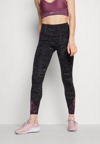 Schwarze, hochtaillierte Leggings mit strukturiertem Muster, die rosa Akzente an den Knöcheln aufweisen und mit einem lila Sport-BH sowie hellrosa Sneakers kombiniert sind.