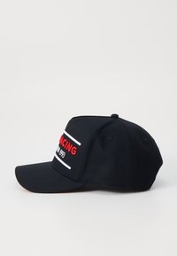 Boné preto com aba curva. Apresenta texto bordado em vermelho "RACING" e listras horizontais brancas. O tecido tem uma textura suave.