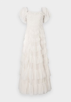 Vestido blanco de volantes hecho de tela liviana y transparente con acentos fruncidos. Presenta mangas abullonadas y un cuerpo fruncido. Texturizado con pequeños lunares.