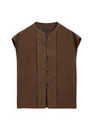 Brown linen tunic with short, wide sleeves, featuring a round collar and six front button closures, highlighted by contrasting stitching details.