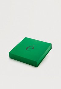 Πράσινο ορθογώνιο κουτί δώρου με λεία υφή, που φέρει ένα στιλιζαρισμένο μαύρο γράμμα «é» και ένα κόκκινο διακοσμητικό στο καπάκι.