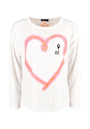 White long-sleeve shirt featuring a pink sequined heart design and the text "YOU ARE HERE". Rounded neckline with a relaxed fit.