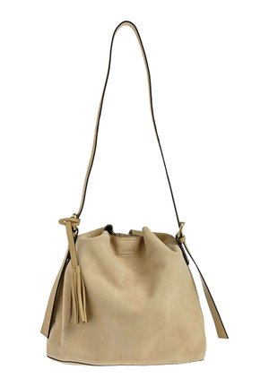 Sac seau en daim beige avec longue bandoulière et détail de pompon sur le côté, présentant une structure souple et décontractée.