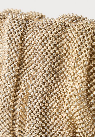 Χρυσό ύφασμα πυκνά καλυμμένο με μικρούς, λαμπερούς στρας διατεταγμένους σε κυματιστό, υφασμάτινο μοτίβο.