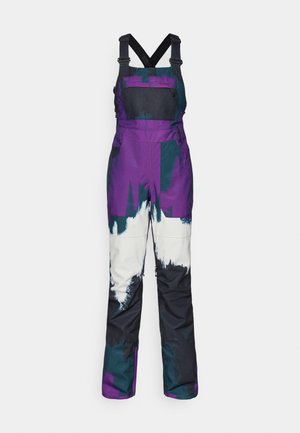 Purple and teal snow overalls with adjustable black straps, featuring a chest pocket, bold color blocks, and a water-resistant design.