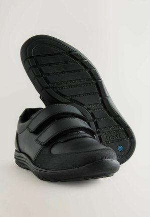 Schwarze Schuhe aus einer Kombination von Leder und Stoffmaterialien, mit sicheren Klettverschlüssen und einer strukturierten Gummisohle für besseren Halt.