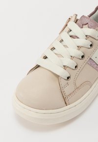 Baskets en cuir beige avec des lacets blancs, semelle en caoutchouc texturée et accents en paillettes roses sur la languette. Bout arrondi et détails cousus.